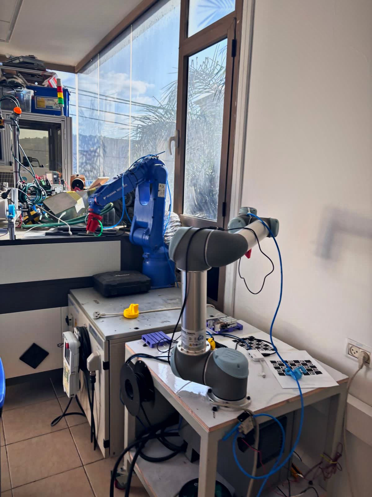 Blue Yaskawa Motoman industrial arm beside a UR5 cobot in the lab