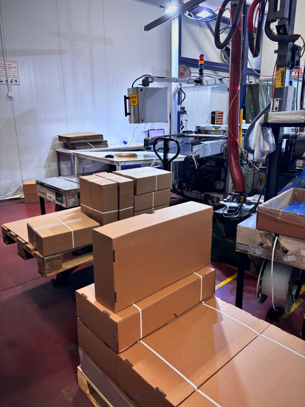Factory packing line with stacked cardboard boxes and packaging machinery
