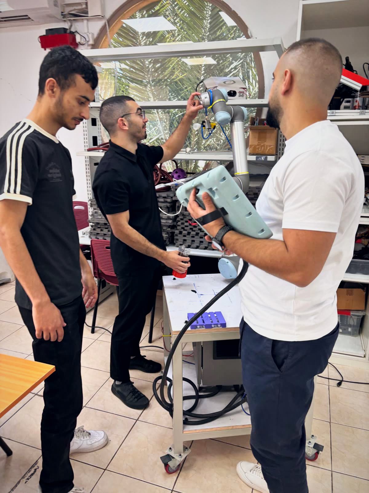 Three RuRobotics team members teaching a UR5 cobot using the teach pendant